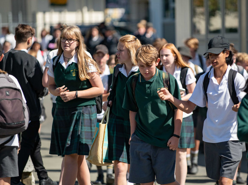 Group of students walking through classroom corridor